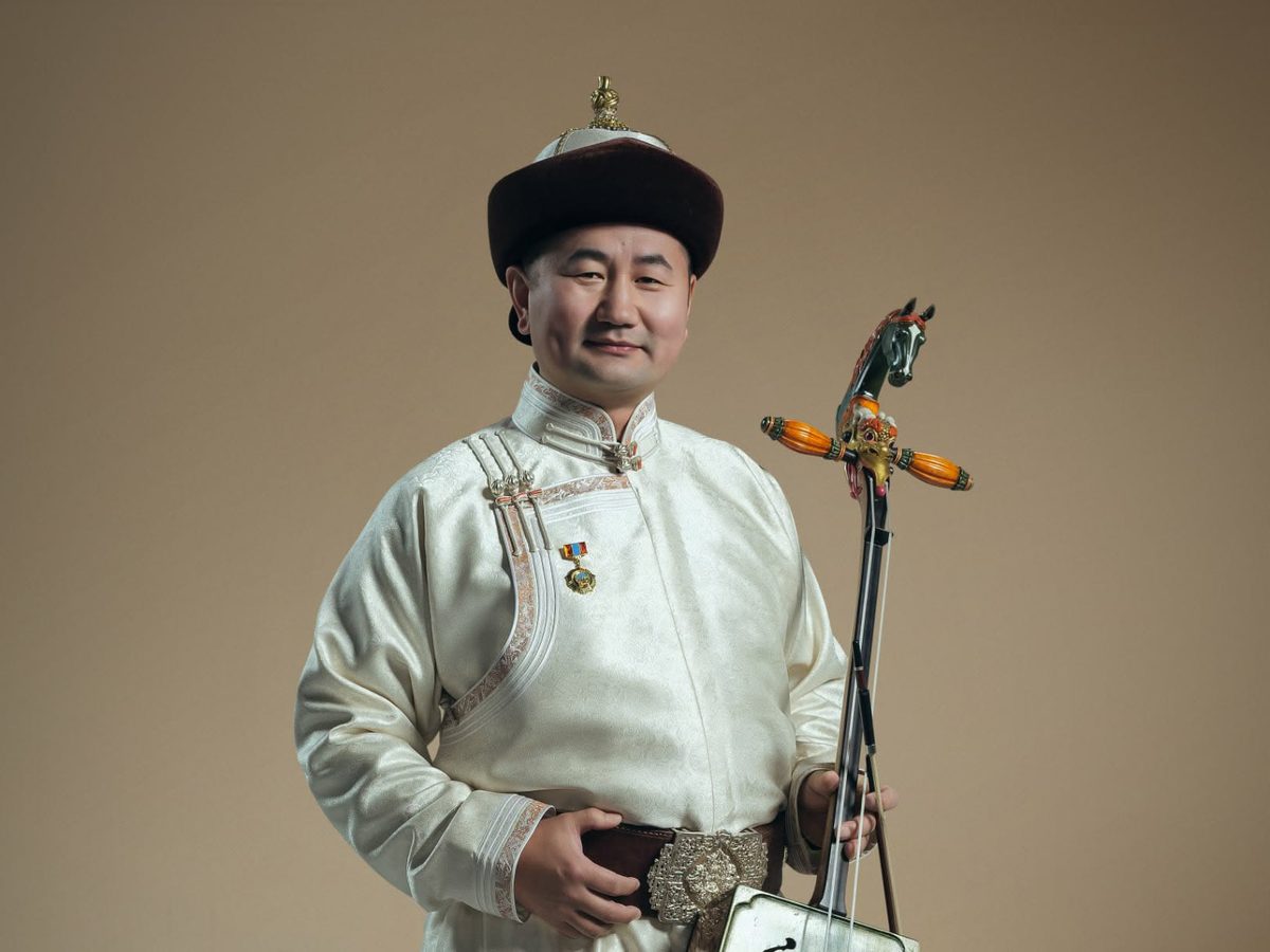 N. Ashit in a white deel, holding a morin khuur
